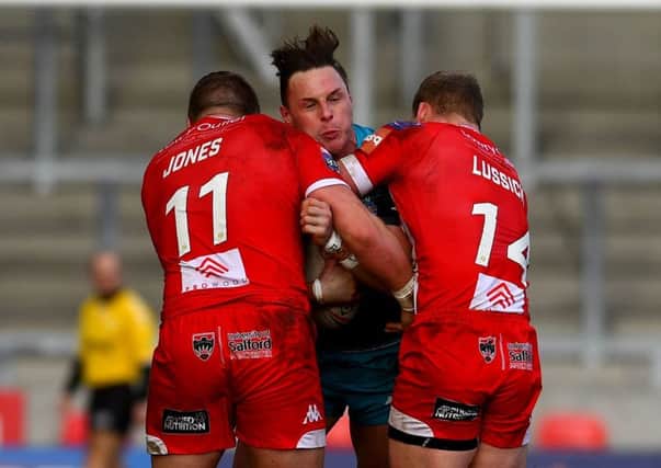 James Donaldson is tackled by Josh Jones and Joey Lussick of Salford Red Devils.