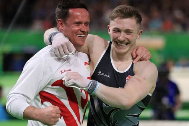 Nile Wilson celebrates winning a Commonwealth Games gold medal in the Men's Individual All-Round final with coach Ben Collie.