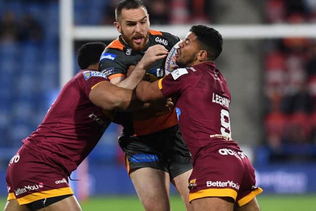 Castleford's new signing Daniel Smith is tackled by Huddersfield's Sebastine Ikahihifo and Kruise Leeming.