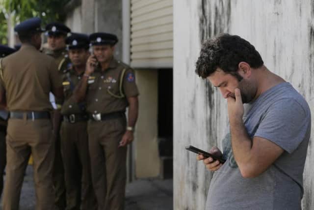 A foreigner checks his mobile phone while waiting outside a mortuary of a hospital, a day after series of blasts, in Colombo, Sri Lanka. PIC: AP Photo/Eranga Jayawardena