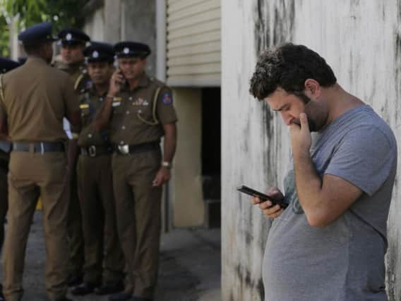 A foreigner checks his mobile phone while waiting outside a mortuary of a hospital, a day after series of blasts, in Colombo, Sri Lanka. PIC: AP Photo/Eranga Jayawardena