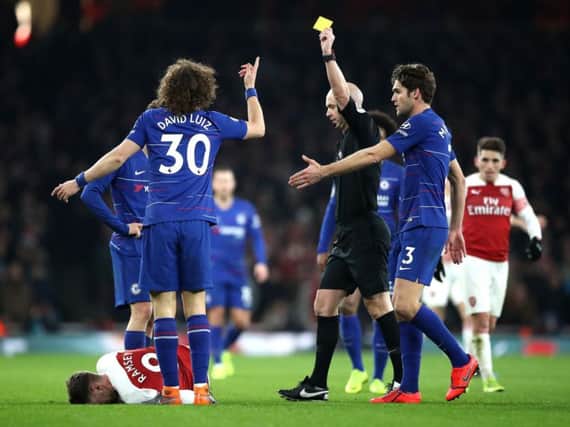 Referee Anthony Taylor brandishes a yellow card during a clash between Chelsea and Arsenal.