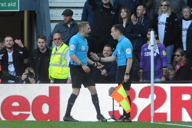 Referee Craig Pawson consults linesman Eddie Smart.