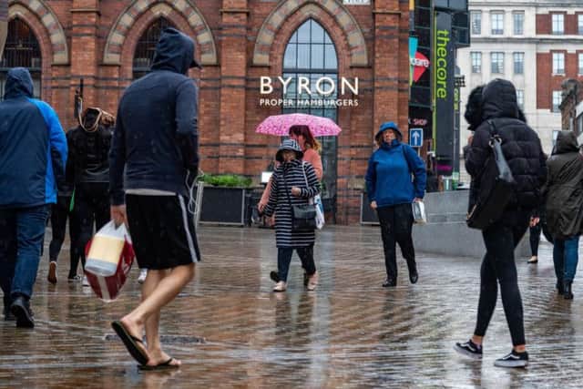 Office workers and shoppers sheltering from the rain whilst in the centre of Leeds.
