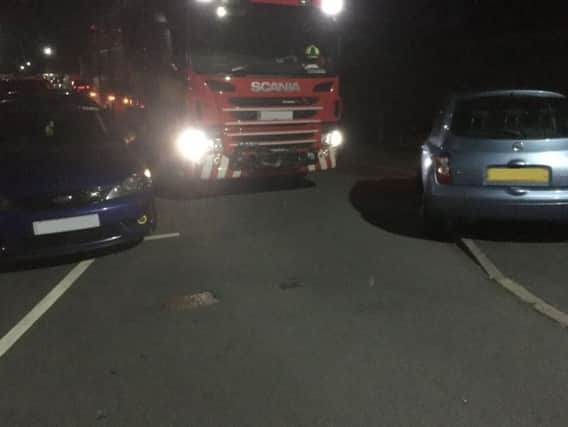 Two parked cars block a fire engine on the way to an emergency