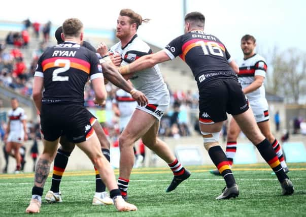 Anthony Mullally of Toronto Wolfpack is tackled by Ethan Ryan and James Green of Bradford Bulls.