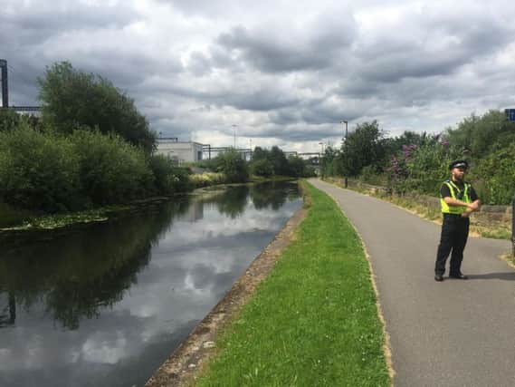 A police officer guards the canal near Whitehall Road.