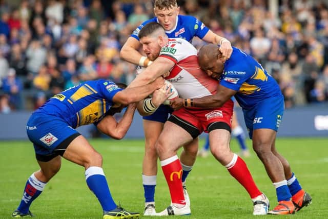 Former Leeds player Mitch Garbutt is held by the Rhinos' defence.