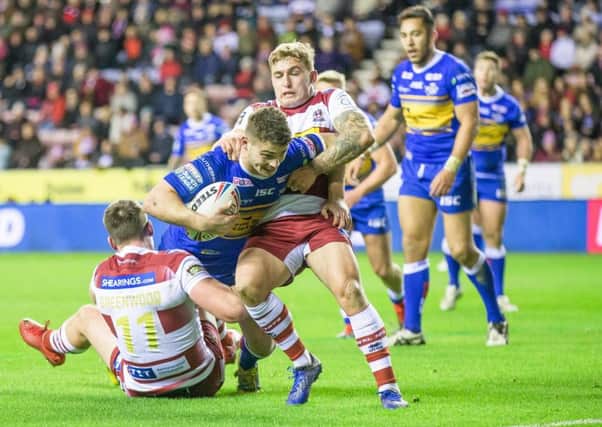 Stevie Ward is tackled by Joe Greenwood and Sam Powell of Wigan Warriors.