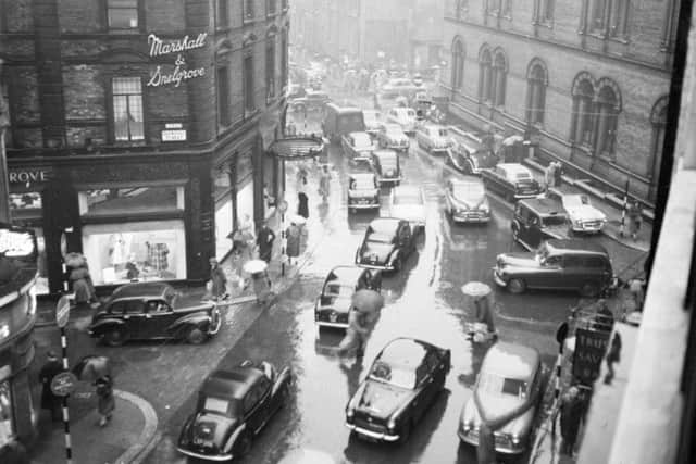 Traffic jam on Basinghall Street. People running across the road with umbrellas. Marshall and Snelgrove shop. Taken between 1960 and 1969.