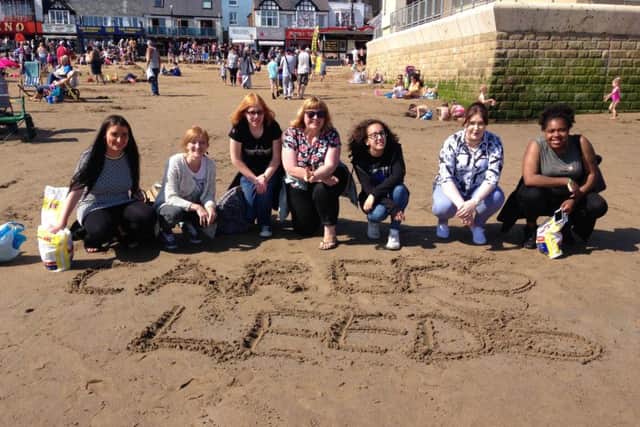 Members of Carers Leeds write its name in the sand during a trip to the beach.