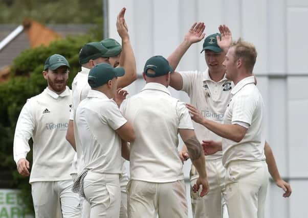 Otley players celebrate a wicket by Dermot Reeve, right, who took four wickets in the win over visitors Pool to keep them clear at the top of Division 1. PIC: Steve Riding