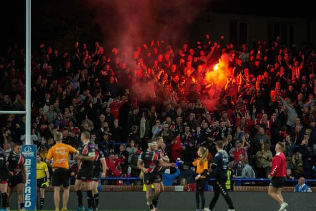 Salford Red Devils fans light a flare after their third try.
