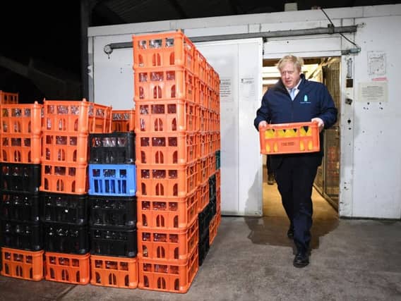 Prime Minister Boris Johnson carries a crate during a visit to Greenside Farm Business Park. Photo: Stefan Rousseau/PA Wire