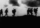 British troops in silhouette march towards trenches near Ypres at the Western Front during the First World War.