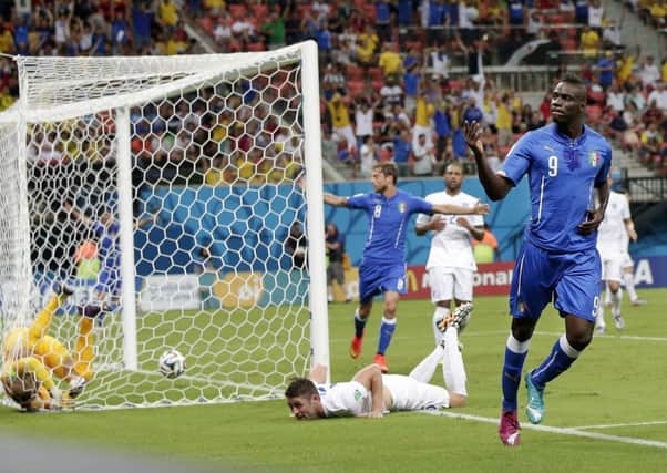 Italy's Mario Balotelli (9) celebrates after getting the ball past England's goalkeeper Joe Hart, left, and Gary Cahill, center, to score his side's second goal.