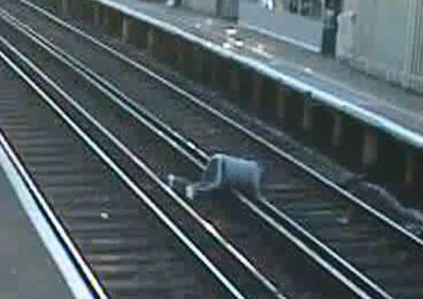 A man can be seen cycling on the platform before jumping off his bike to quickly dash across the track