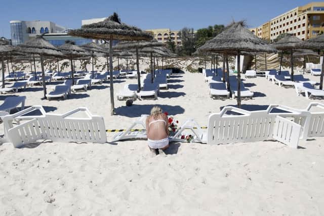 A young woman lays flowers at the scene of a shooting in Sousse, Tunisia, Saturday, June 27, 2015. The morning after a lone gunman killed at tens of people at a beach resort in Tunisia, busloads of tourists are heading to the nearby Enfidha-Hammamet airport hoping to return to their home countries. (AP Photo/Darko Vojinovic)