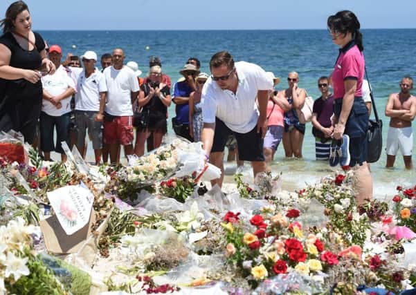 Tourists lay flowers on the beach on July 3, 2015, during a ceremony in memory of those killed