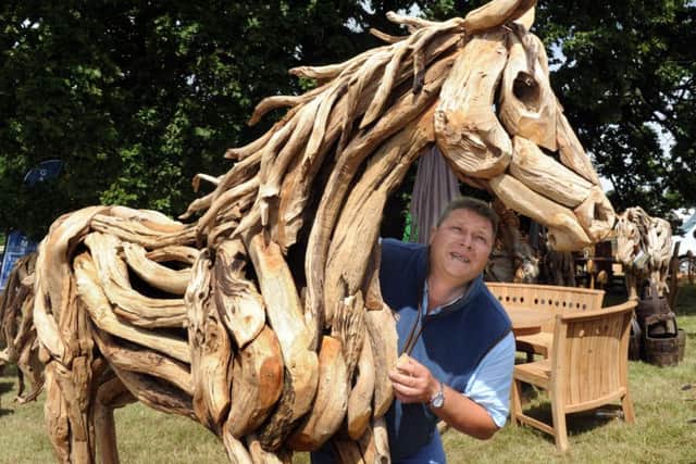 Philip Fry from 'Simply The Best' who sell driftwood sculptures and garden furniture, putting one of the teak driftwood horse sculptures by artist Abdul Ghofur into position on their stand. (Gl1006/66b)