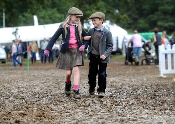 Heidi Drummond, aged eight, with her brother Bill Drummond, from Wensleydale, walk through the muddy conditions at the CLA Game Fair at Harewood House. (SH100142011a)  Picture: Simon Hulme