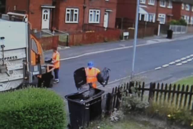 The bin man took the bag out of one bin and left it on the side of the street