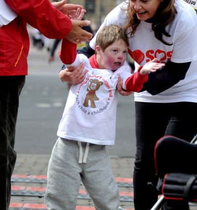 Toby Lancaster, 6, being helped over the finishing line, after taking part in the Junior Race at Leeds Half Marathon in 2013