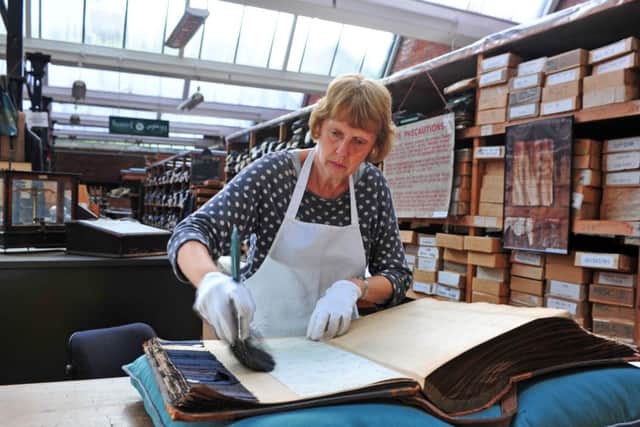 Volunteer Wendy Adams cleans a guard book in the textile archive held at Sunny Bank Mills in Farsley. Picture by Tony Johnson.