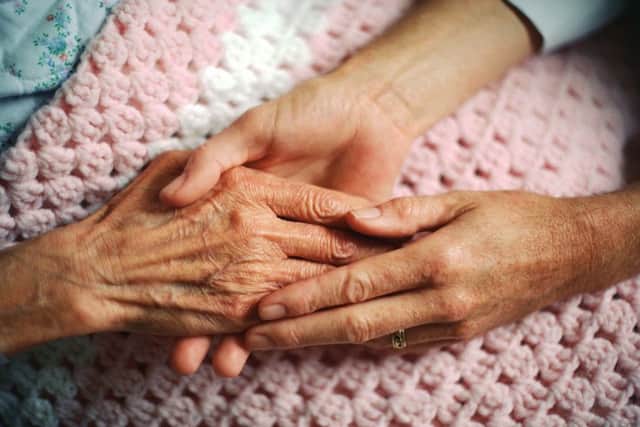 A geriatrician holds the hand of an elderly woman with arthritis.