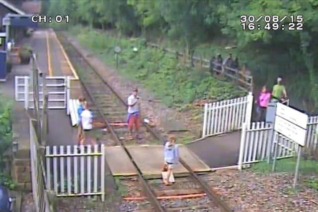 Children sitting on the rails while having their photo taken, and adults crossing the line,  at Matlock Bath station in Derbyshire