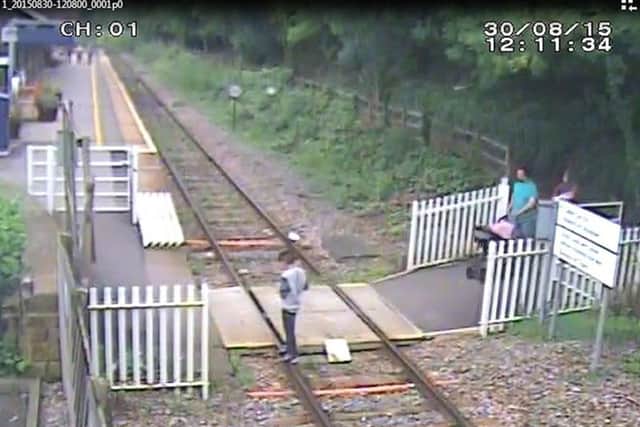 Children sitting on the rails while having their photo taken, and adults crossing the line,  at Matlock Bath station in Derbyshire