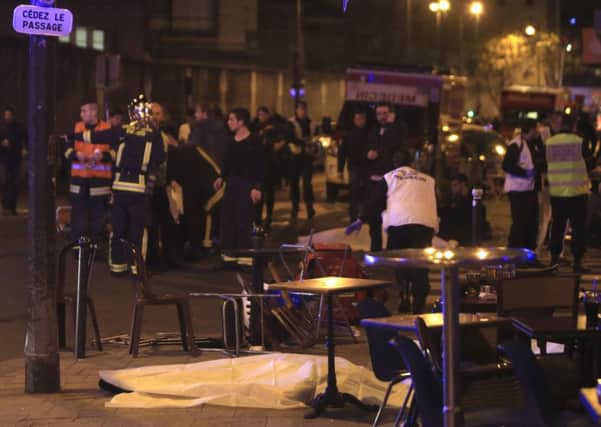 Rescue workers and medics work by victims in a Paris restaurant, Friday, Nov. 13, 2015. Police officials in France on Friday reported a shootout in a Paris restaurant and an explosion in a bar near a Paris stadium. It was unclear if the events were linked. (AP Photo/Thibault Camus)