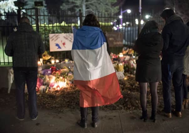 A person wears a French flag at a memorial outside the French Embassy in Ottawa, Ontario, following deadly attacks in Paris on Friday.