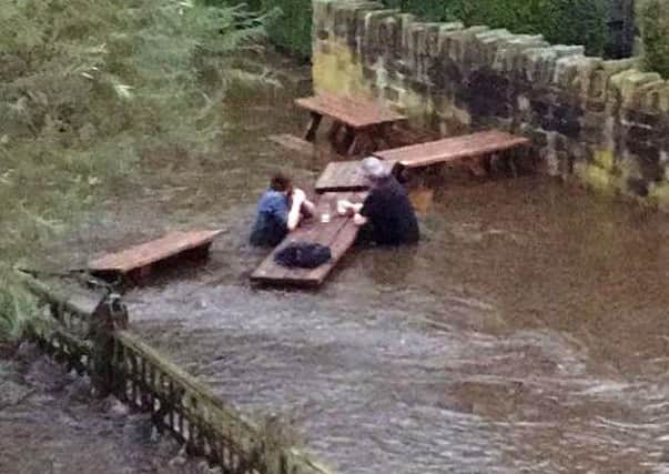 Two people enjoying a pint at the flooded Kirkstall Bridge Inn