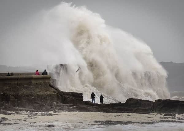 People watch waves close to the harbour wall at Porthcawl, South Wales, on Saturday. Ben Birchall/PA Wire