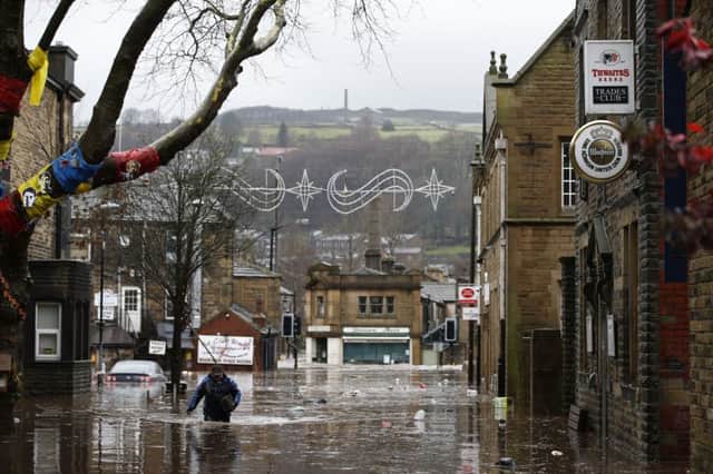 A man wades through flood waters at Hebden Bridge in West Yorkshire, where flood sirens were sounded after torrential downpours. (Pictures: Peter Byrne/PA Wire)