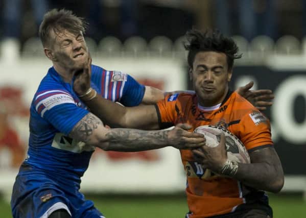 Wakefield's Tom Johnstone is fended off by Castleford's Denny Solomona.