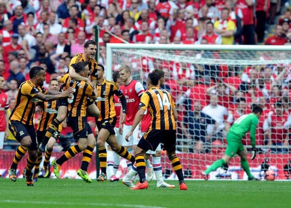 Hull City's Alex Bruce jumps onto team-mate James Chester, as he celebrates scoring the opening goal against Arsenal in the 2014 FA Cup final.