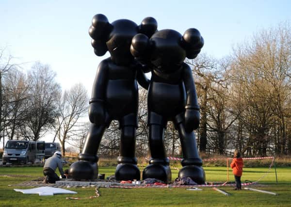 Youngster watches sculpture technicians at Yorkshire Sculpture Park, Wakefield, install six enormous sculptures by renowned American artist KAWS.