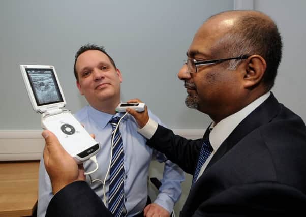 Dr Asoka Weerasinghe demonstrating the VScan handheld ultrasound unit on Rick Miles, from GE Healthcare. Picture by James Hardisty.