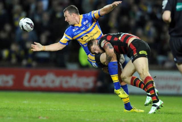 Danny McGuire offloads as Daryl Clark tackles him.