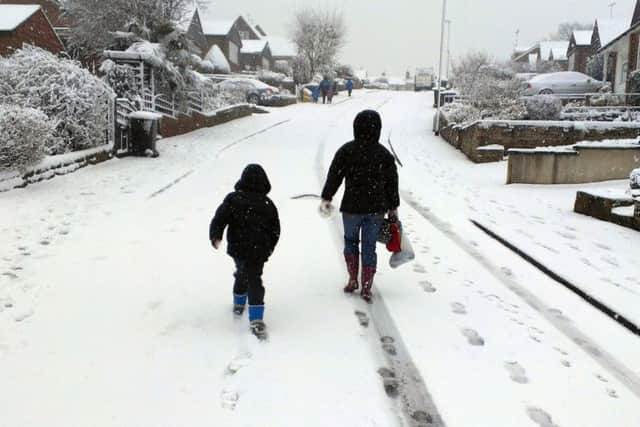 A parent and child make their way to scool in the unseasonal snow in Farsley in March 2013