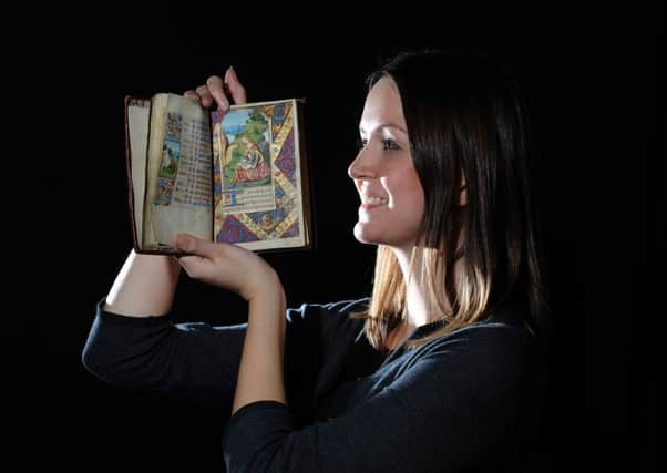 Rhian Isaac, collections manager at Leeds Central Library, holding a 15th Century Illuminated manuscript.