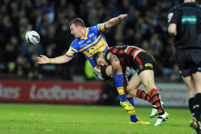Rhinos Danny McGuire offloads as Wolves Daryl Clark hits.  (Picture: Tony Johnson)