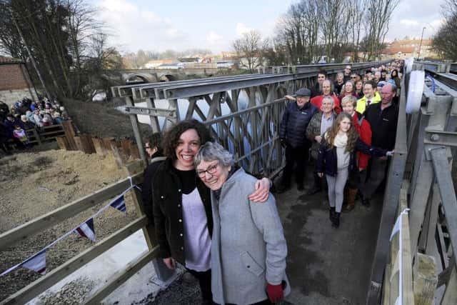 Barbara and Chrissie Wilson, a mother and daughter who live on opposite sides of the River Wharfe in Tadcaster, make their first crossing over a temporary footbridge which was built following the collapse of the main bridge after severe flooding.