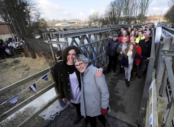 Barbara and Chrissie Wilson, a mother and daughter who live on opposite sides of the River Wharfe in Tadcaster, make their first crossing over a temporary footbridge which was built following the collapse of the main bridge after severe flooding.