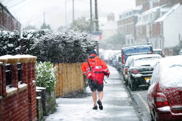 A postman delivers mail in shorts around Beverley in the snow.