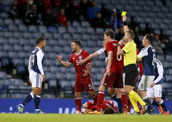 Scotland's Liam Bridcutt (left) is shown the yellow card after fouling Denmark's Erik Sviatchenko (floor). PIC: PA
