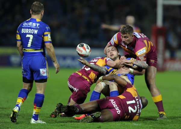 Rhinos Luke Briscoe releases the ball as he is held by Kyle Wood, Michael Lawrence and  Nathan Mason.