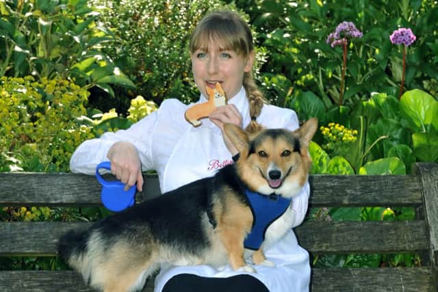 Emma Bulmer from Bettys and Taylors sampling a Corgi biscuits they have made to celebrate the Queens 90th birthday with  Buddy the  Corgi  who modelled for the Corgi biscuits.